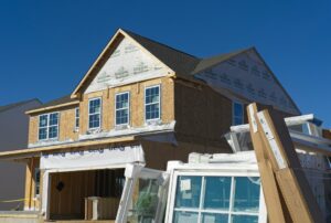 Homeowner comparing siding, flooring, and insulation samples beside renovation plans.