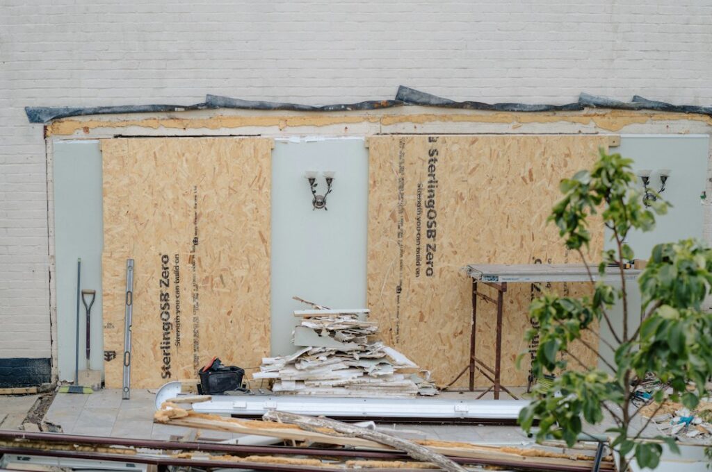 Homeowners compare wood samples, insulation, reclaimed brick, and recycled materials on a workbench.